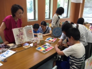 おとなの人に見てもらいながら作業をしている子供たちの写真