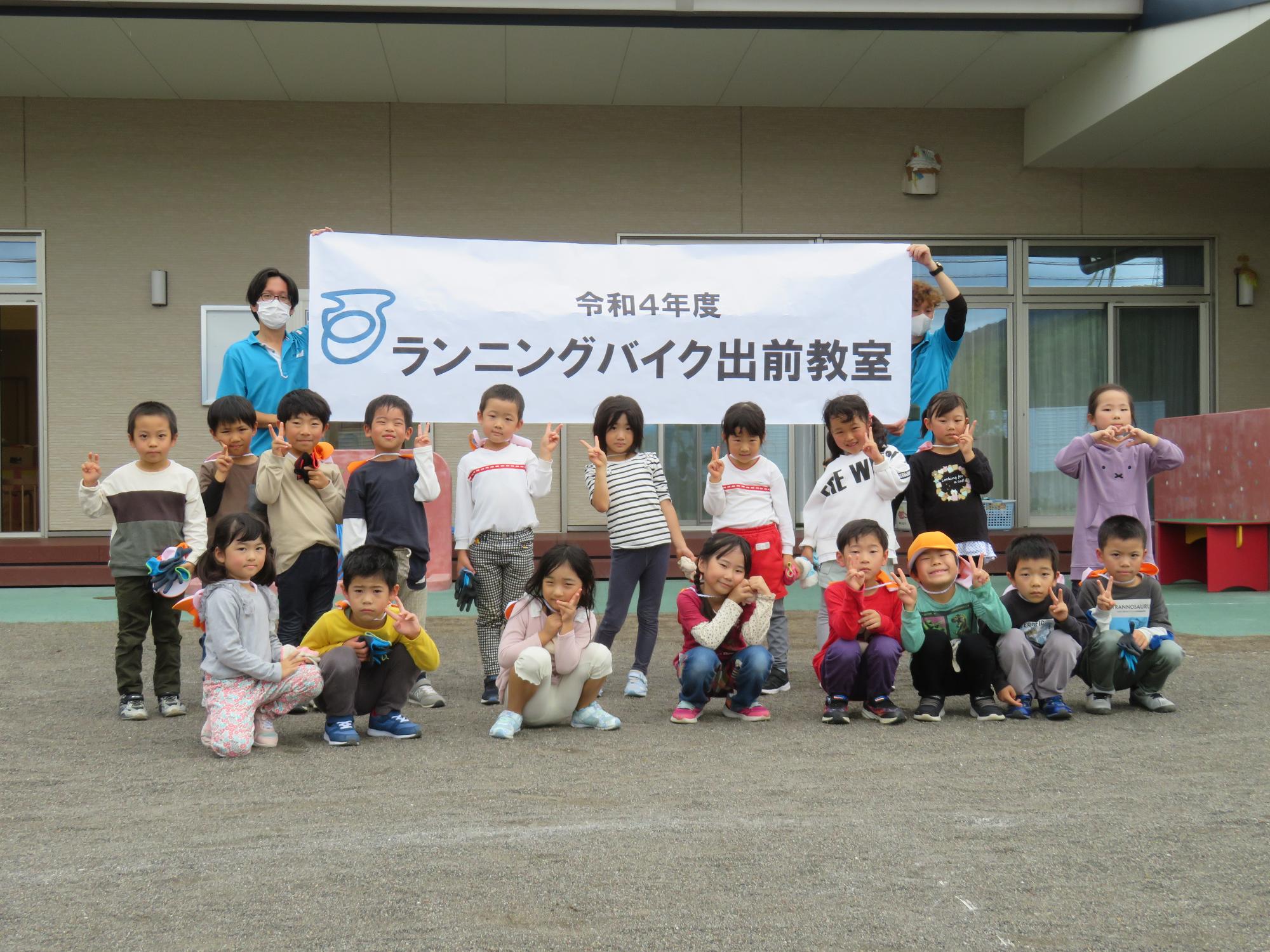 令和4年度ランニングバイク教室と書かれた幕の前で修善寺東こども園の子供たちが並んでいる集合写真