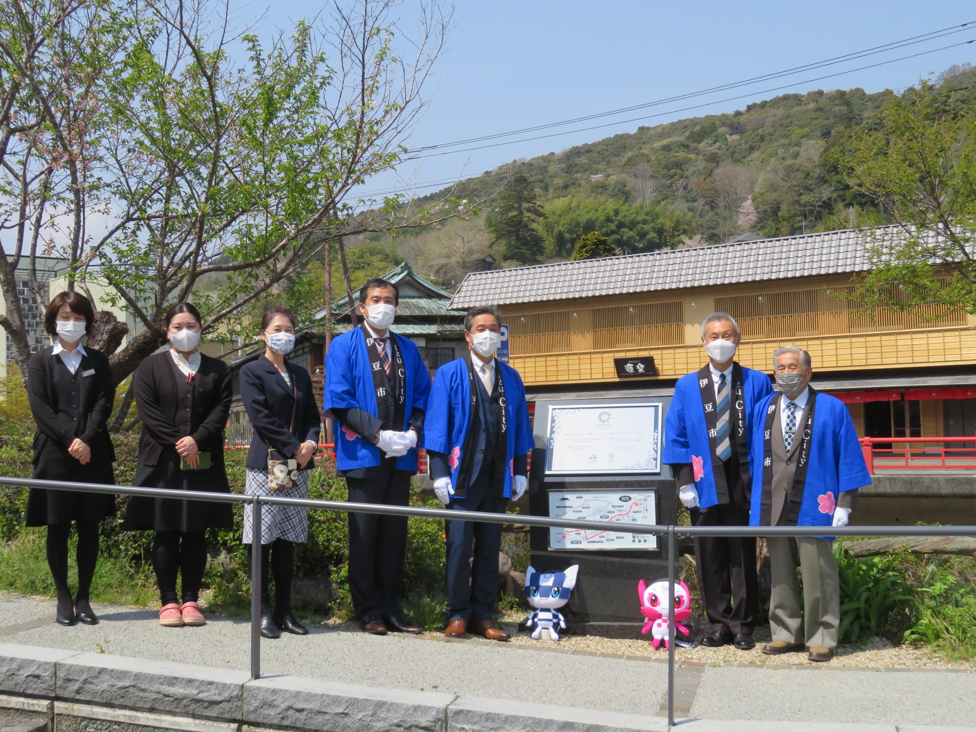 レガシー銘板の両脇に並んでいる法被を着た4名の男性と、女性3名の記念写真