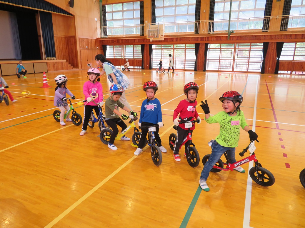 ヘルメットを被り自転車にまたがった6名の子供たちが縦に並んでいる写真