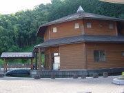 2階建てで、木目の壁の多角形の建物の外観写真
