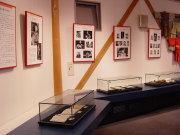 透明ケースの中に展示された資料や、赤い額に入った写真や資料が展示されている展示室の写真