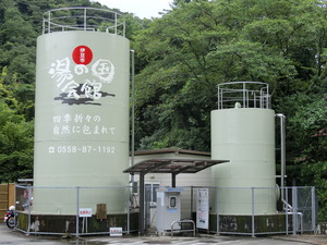 湯の国会館と書かれた大きなタンクが2つある温泉スタンドの写真