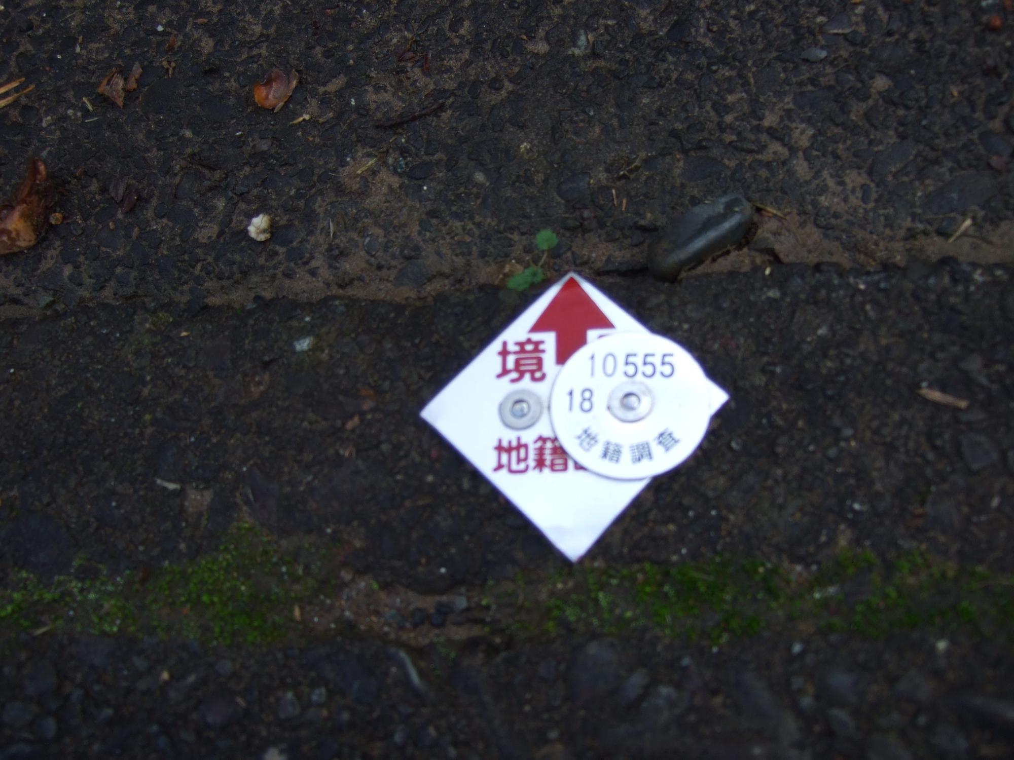 道路の境界の位置をに赤色プレートで表している写真