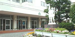 たくさんの花が飾られ、つないだ手を高く上にあげるポーズの像が置かれている土肥小中一貫校の写真