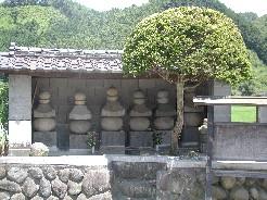 石垣の上に6基の五輪塔が横に並んでいる加藤景廉一族の墓の墓の写真
