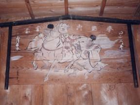 木の札に白い馬と着物を着た男性の絵が描かれている絵馬の写真