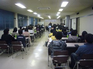 着席している総会参加者と、演台に立つ男性の写真
