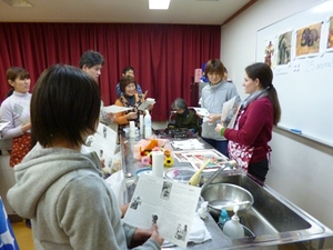 参加者の男女が手元の資料を見ながら、外国人女性の話を聞いている写真