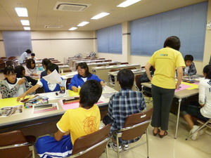 机の上に画用紙や写真を並べ、資料を作っている生徒たちの写真