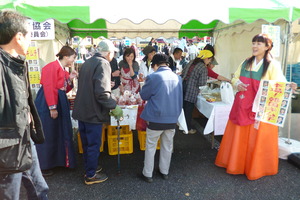 伊豆市交流協会の出展ブースに集まる来場者の方やチマチョゴリを着た女性の写真