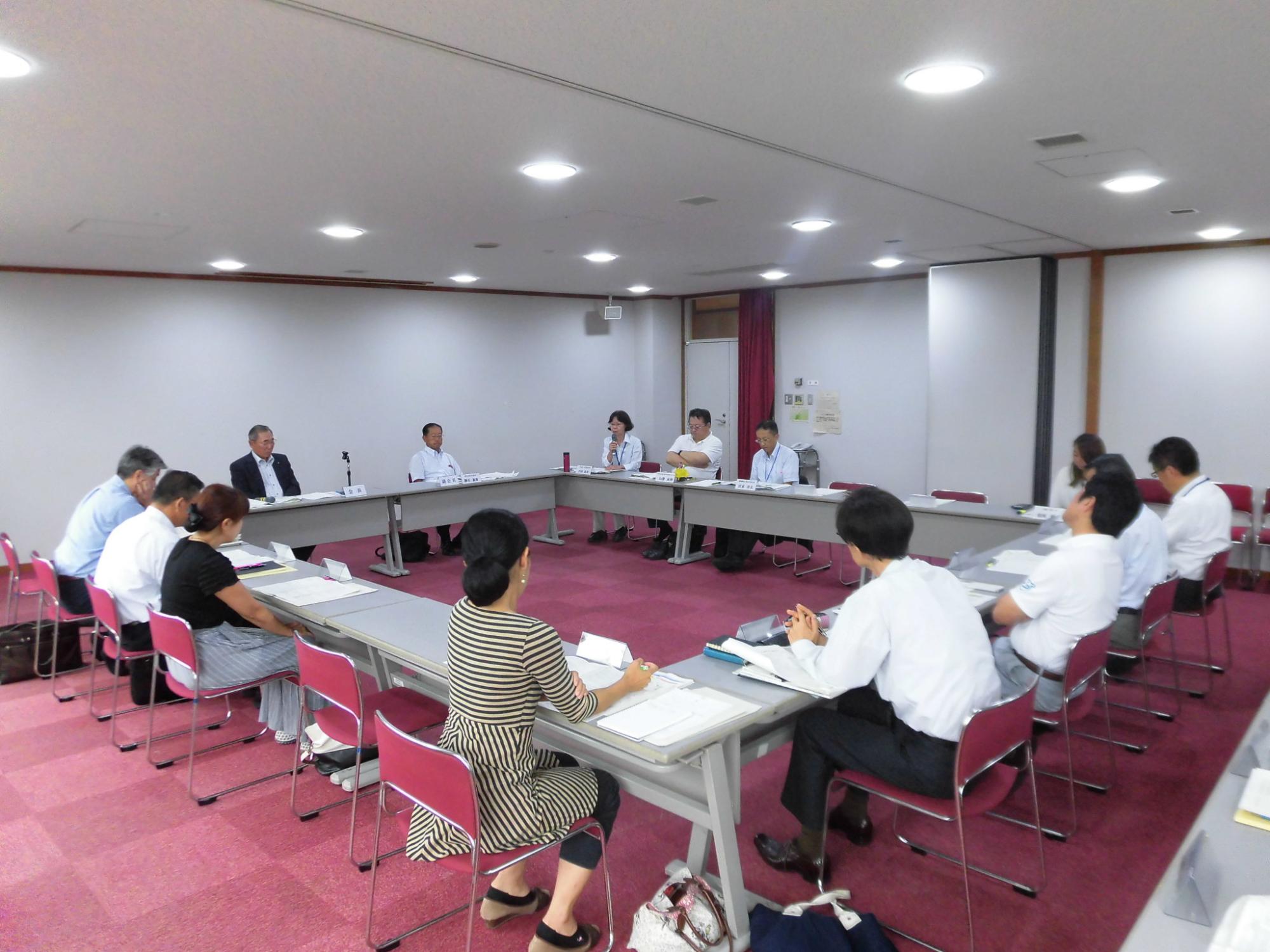 内側に向かい合うように長方形に並べられた席に座り、話し合いをしている様子の写真