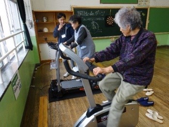 教室だった部屋に置かれたルームランナーやフィットネスバイクで運動をする高齢者の方の写真