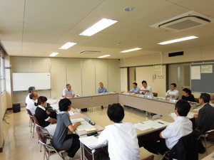 長方形に並べられた席に座り、話し合いをしている様子の写真