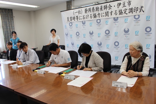 関係者6人が横並びで座り、協定書に調印をしている様子の写真