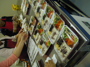 調理台の上にお弁当が並べられていて作業をしている推進員たちの手元が写っている写真