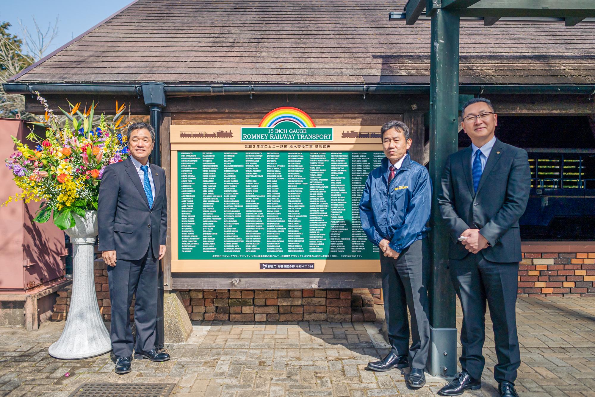 設置した銘板を挟んで、菊地市長、山下支配人、佐藤副市長の記念写真