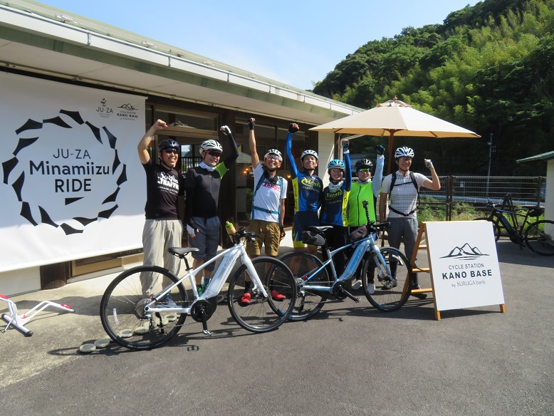 ヘルメットを付け、サングラスをした参加者が、拳を上にあげて並んでいる記念写真