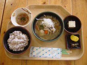 中央に猪汁、周りにご飯や漬物、豆腐などが置かれている写真