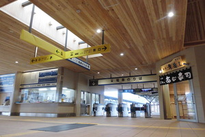 木の板で出来た天井、奥には電車のりばと書かれた改札口のある、修善寺駅内装の写真