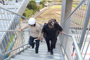 ヘルメットや帽子を被った方々が避難タワーの階段を登っている写真