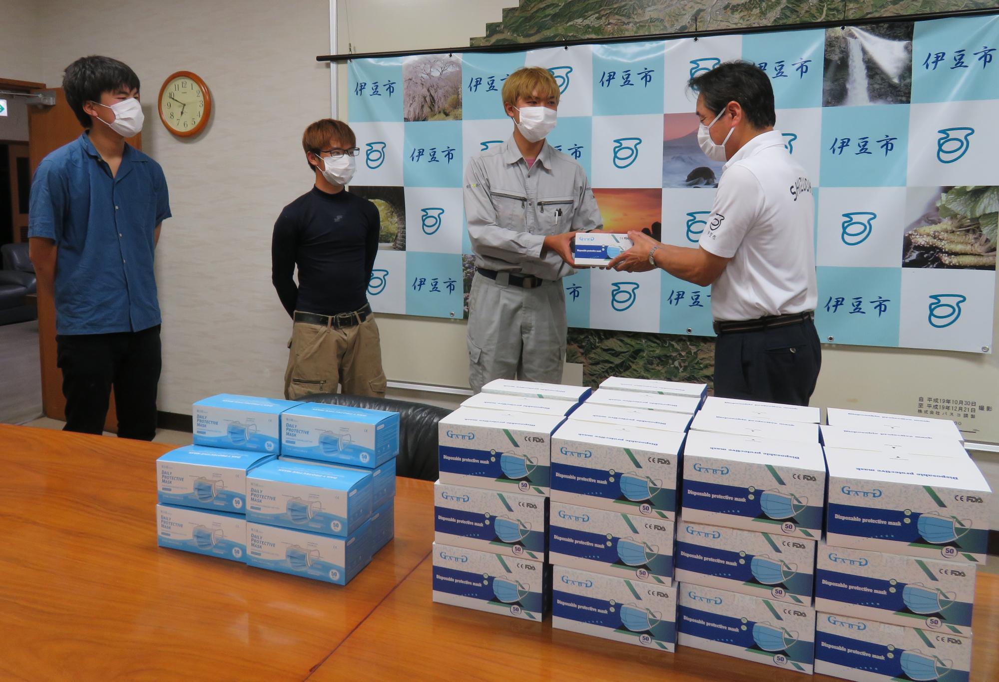 伊豆総合高等学校卒業生有志の代表の方が箱に入ったマスクを手渡している写真