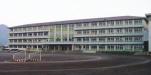 校庭にフットサルゴールが置かれている修善寺中学校の校庭と4階建の校舎の写真