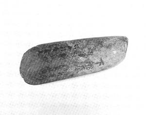 両端のうち片方は丸みを帯び、もう片方は少し尖ったような形をしている石斧の白黒写真