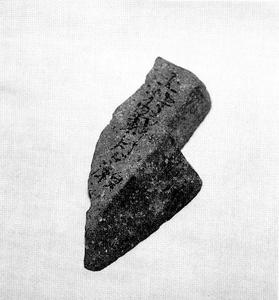 包丁のような刃と持ち手のような形のところに字が彫られている石の白黒写真