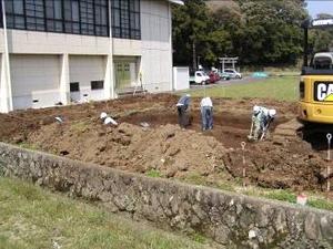 作業員が、スコップなどを使って地面を掘っている写真