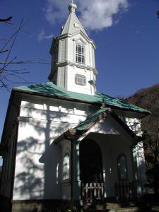 白い外壁に緑色の屋根で尖塔と呼ばれる細長く先のとがった屋根が付いた2階部分がある聖堂の写真