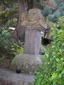 右側に葉っぱが茂っていて、奥に苔の生えた石塔が置かれている大見小藤太成家の墓の写真