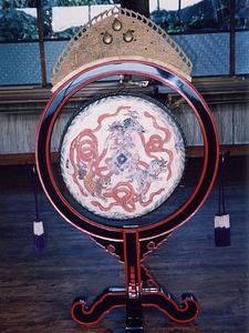 太鼓の中央に蛇のようなものが描かれた祭祀用太鼓の写真