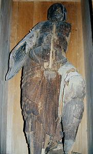 人の形をしていて、腕部分がなくなっている木造天部形立像が倒して置かれている写真