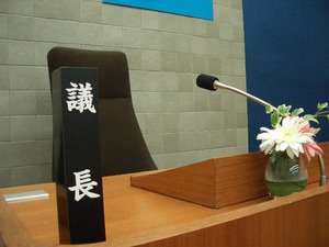 マイクや立札が置かれている議長席の写真