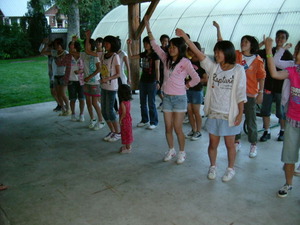 3列に並んで立った生徒たちが右手を挙げて踊りながら歌っている様子の写真