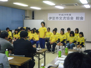 着席している総会参加者の前と向かい合って着席している黄色いシャツを着た男女の写真