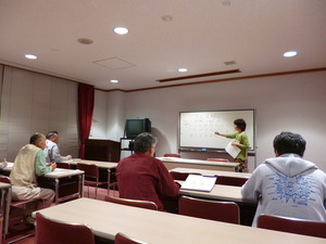 着席している中国語教室の参加者と、ホワイトボードの前に立つ女性の写真