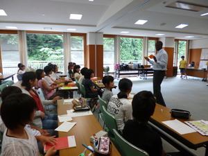 前に立ち授業をする外国人の講師の方の話を座って聞いている生徒たちの写真