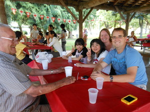 赤いテーブルクロスの敷かれた席に座りピースをしている女の子2人と3人のホストファミリーの写真