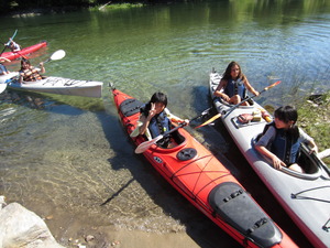 水の澄んだきれいな川でカヌー体験をしている生徒たちの写真
