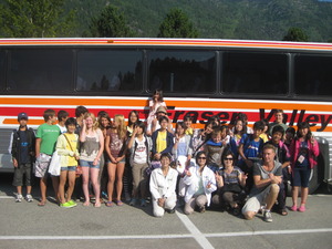 大きなバスの前に立つ生徒たちとホストファミリーの集合写真
