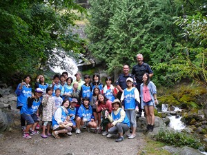 お揃いの青いビブスを着て、流れる滝の前に立つ参加者たちの集合写真