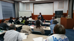 教卓に立ち講義をする小林仁美先生と、席についた生徒たちが講義を聞く様子の写真