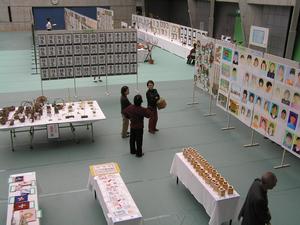 書道や絵、工芸品などの作品が有孔ボードや机の上に展示されている様子の写真