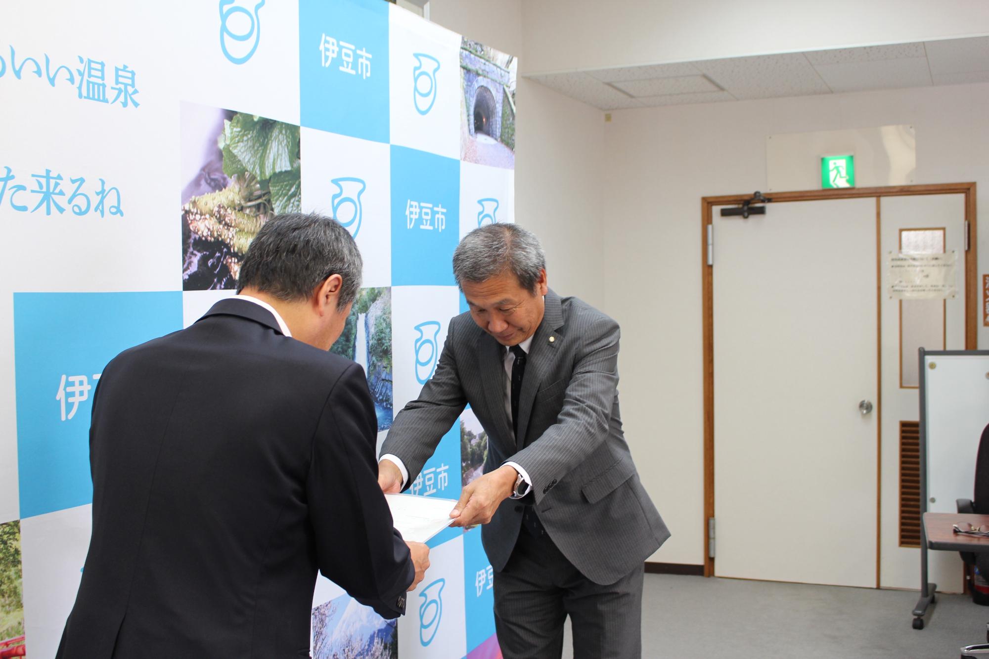 山田健次審議会会長から市長へ答申書が手渡された様子の写真